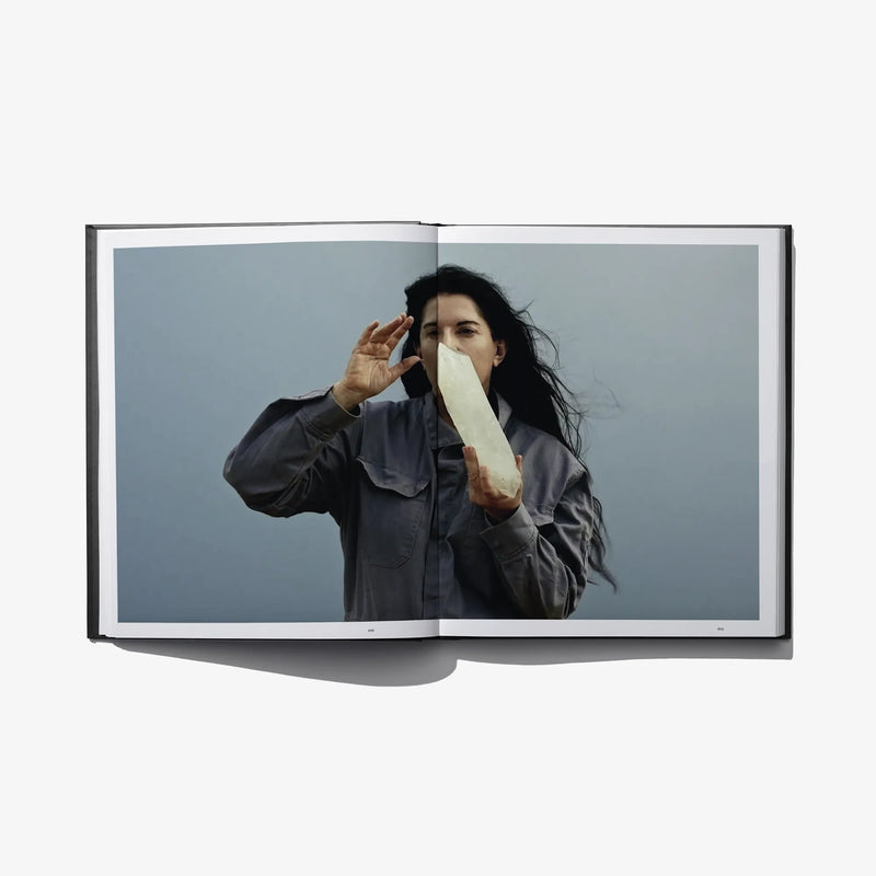 Open art book spread with person posing with hands to face