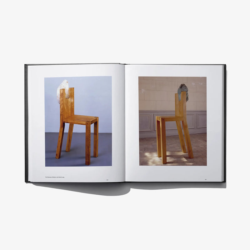 Open photo book spread featuring two wooden chairs with sculptural headpiece-like coverings.