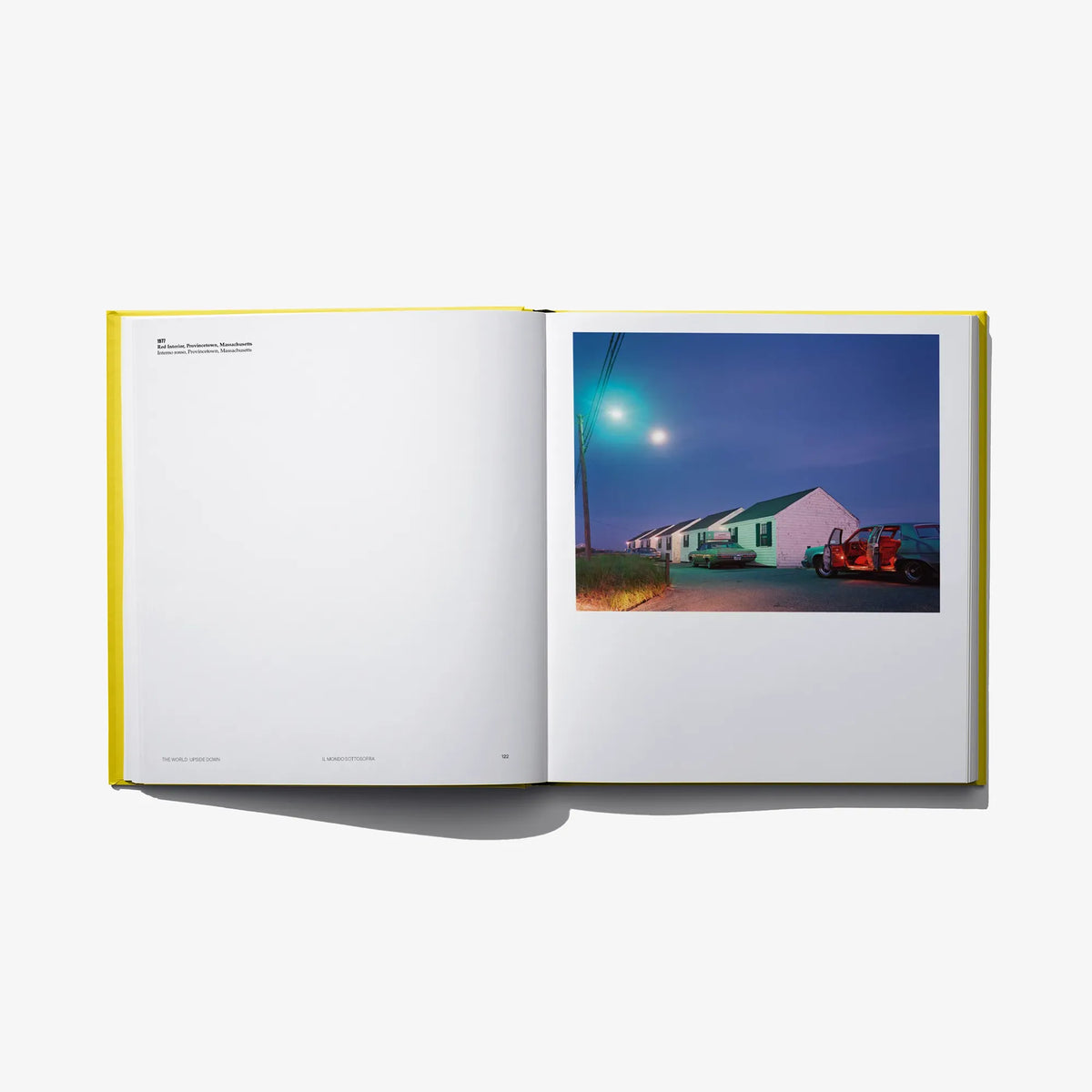 Open photo book spread with a blue-toned street and houses photo on the right.