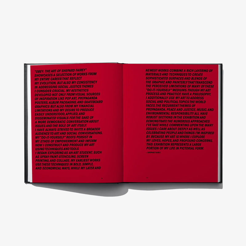 Hardcover art book open to red pages with dense printed text blocks on both spreads
