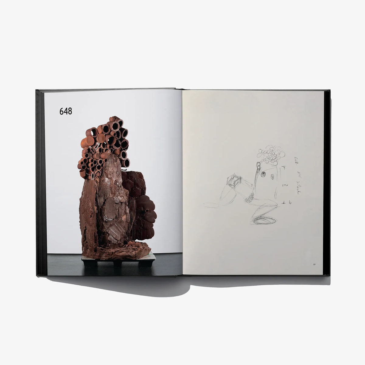 Open sketchbook spread with brown sculpture photo and pencil figure sketch
