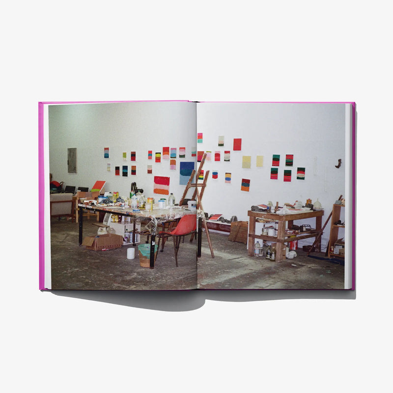 Open art book showing a studio scene photo on the right page