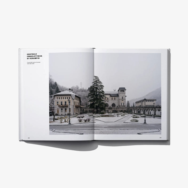 Open hardcover book featuring a monochrome landscape with buildings and hills.