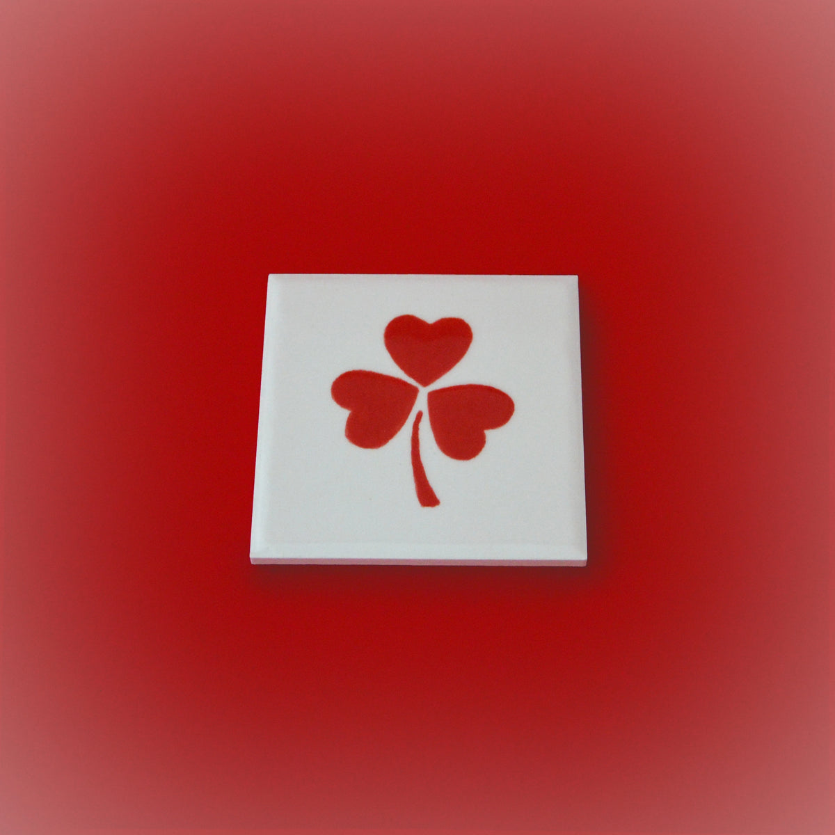 Square ceramic tile with white base and red four-petal heart clover design