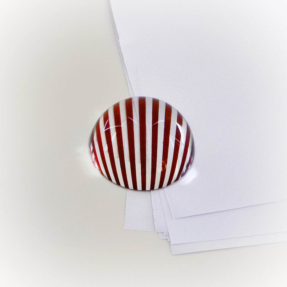 Brera striped red-and-white oval paperweight on papers