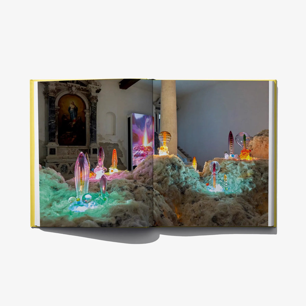 Open book spread showing colorful glass sculptures among cloudy textures