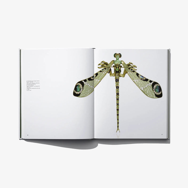 Open art book with a detailed green-and-gold peacock-shaped jewelry diagram