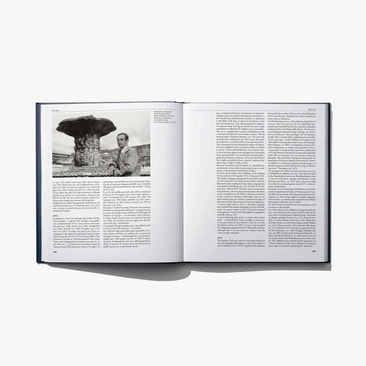 Open art catalog book with large outdoor sculpture photo and dense text columns