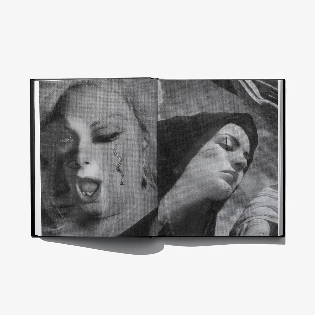 Open art book spread with monochrome face collage and stylized eye details