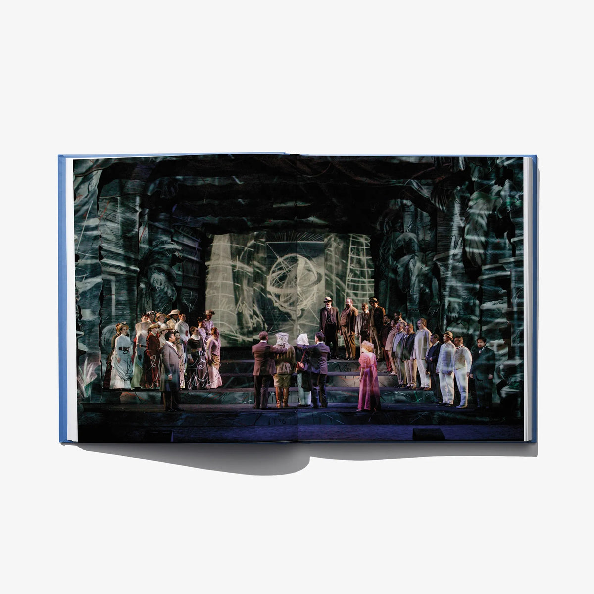 Open art book spread showing a group scene in a dark, ornate hall