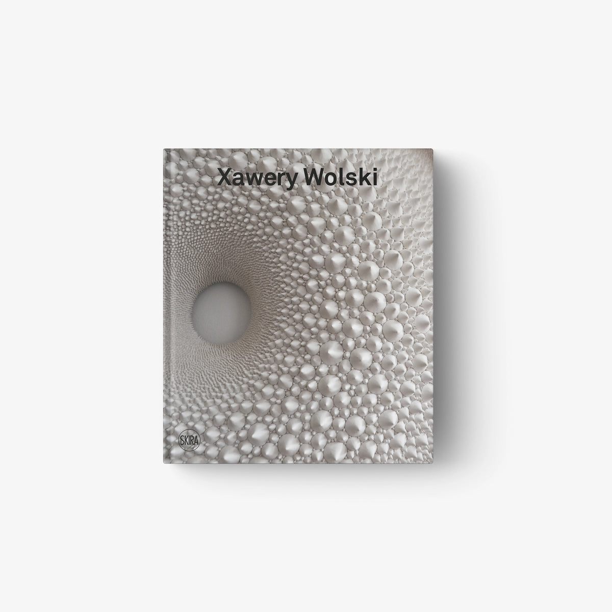 Textured gray sculpture with concentric raised bubbles forming a spiral pattern.