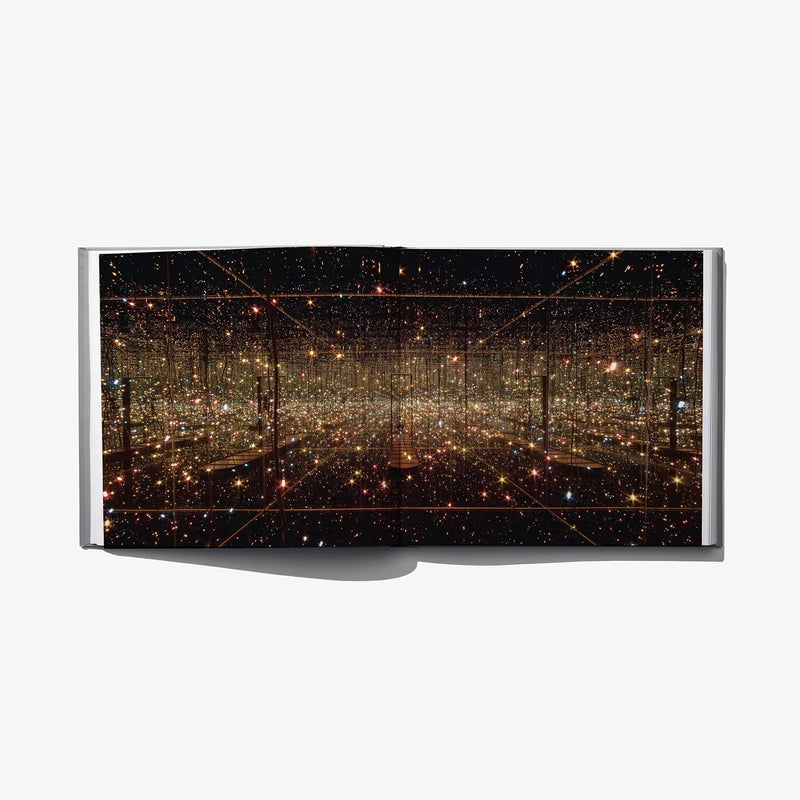 Open art book spread with dark scene of glowing golden dots and lines