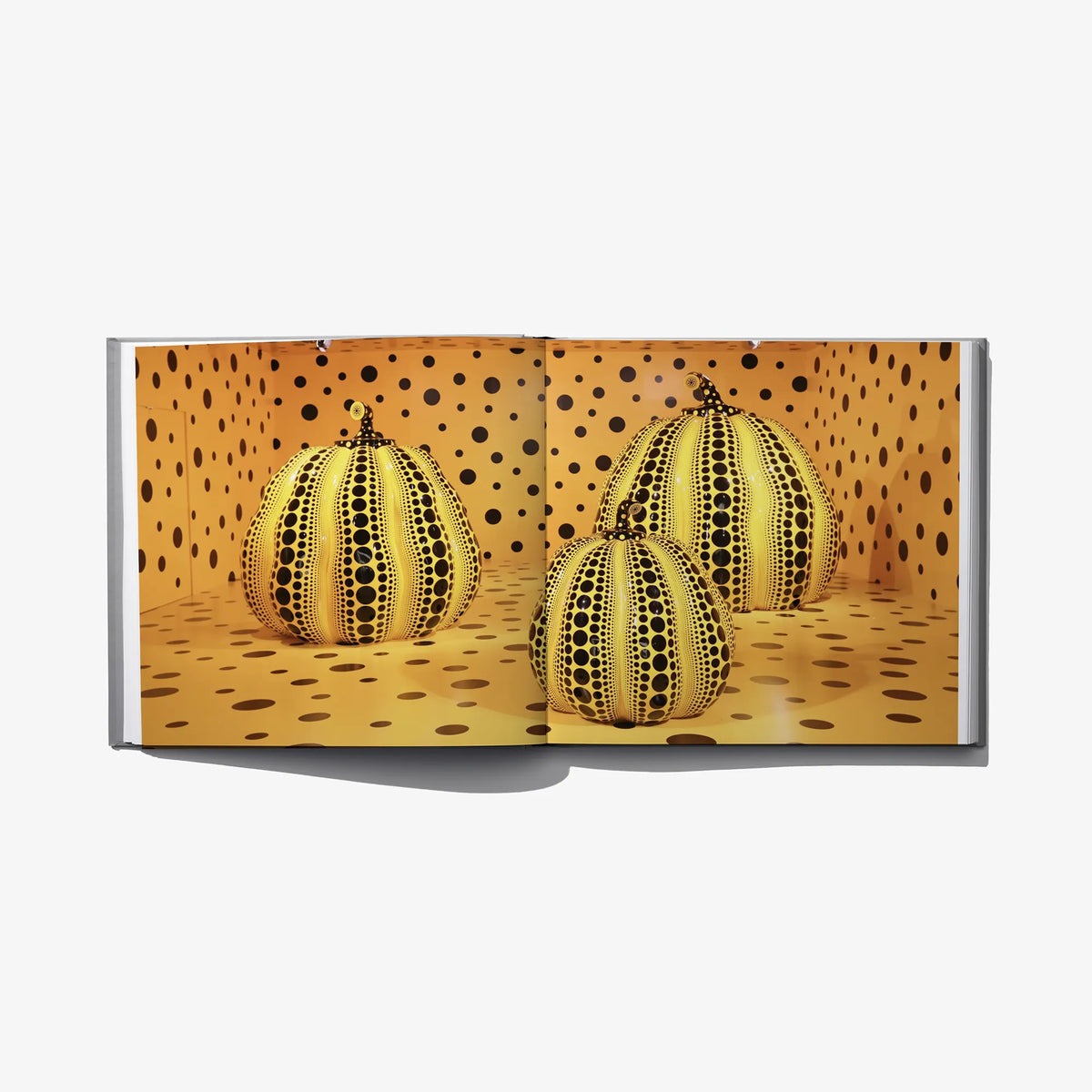 Open art book spread with three yellow polka-dot pumpkins on a warm ground